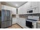 Well-lit kitchen with white cabinets, stainless steel refrigerator, and modern microwave at 509 Delwood Breck St, Ruskin, FL 33570