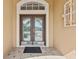 Elegant double front door with decorative glass panels, set in a tan stucco facade with a tiled entrance at 5309 Spectacular Bid Dr, Wesley Chapel, FL 33544