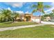 Inviting single-story home featuring a two-car garage, mature palm trees, and a well-kept lawn at 5309 Spectacular Bid Dr, Wesley Chapel, FL 33544