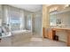 Bright bathroom featuring a soaking tub, glass-enclosed shower, double vanity with wood cabinets, and tiled flooring at 5518 Luminar Pointe Ln, Apollo Beach, FL 33572