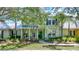 Beautifully landscaped front yard with mature trees and a charming two-story home with a welcoming front porch at 5518 Luminar Pointe Ln, Apollo Beach, FL 33572