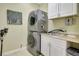 Laundry room featuring stacked washer and dryer, sink with white cabinets, and artwork at 5518 Luminar Pointe Ln, Apollo Beach, FL 33572