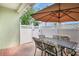 A cozy outdoor dining area with an umbrella-covered table and chairs on a brick patio with white fence at 5518 Luminar Pointe Ln, Apollo Beach, FL 33572
