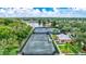 An aerial view of community tennis courts alongside a serene lake and lush green landscaping at 5518 Luminar Pointe Ln, Apollo Beach, FL 33572