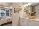 Bathroom featuring double vanity with white cabinetry and quartz countertop, decorative mirror, and bedroom view at 719 Steel Dr, Apollo Beach, FL 33572