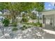 A tranquil backyard with lush landscaping, a manicured lawn, stone accents, and ample shade from mature trees at 759 Lantana Ave, Clearwater Beach, FL 33767