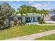 Landscaped front yard featuring a quaint home with a blue door, palm trees and well-maintained lawn at 759 Lantana Ave, Clearwater Beach, FL 33767