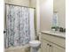 Well-lit bathroom featuring a shower with a decorative floral curtain and granite vanity at 8605 Grand Alberato Rd, Tampa, FL 33647