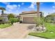 Attractive home showcasing a brick driveway, manicured lawn, and a well-maintained two-car garage at 8605 Grand Alberato Rd, Tampa, FL 33647