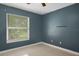 Cozy bedroom with a window, neutral tile floor, and painted blue walls at 915 S Miller Rd, Valrico, FL 33594