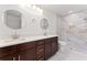 Renovated bathroom with double sinks, modern lighting, walk-in shower, and tile floors at 10237 Carrin Rd, Spring Hill, FL 34608
