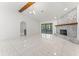 Spacious living area featuring a stone fireplace, vaulted ceiling, white tile floors, and access to a screened lanai at 10237 Carrin Rd, Spring Hill, FL 34608