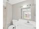 A clean bathroom with white walls, white vanity and tile, and views of the backyard through the window at 11896 104Th Ln, Largo, FL 33773