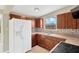 Kitchen features wood cabinets, tile backsplash, white refrigerator, stainless sink, and stone-look countertops at 11896 104Th Ln, Largo, FL 33773