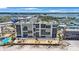 Aerial view of a condo complex on a sandy beach, with a pool and palm trees visible below at 14950 Gulf Blvd # 902, Madeira Beach, FL 33708