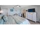 A well-lit bedroom boasts hardwood floors, a dresser, a TV and ocean-themed artwork at 14950 Gulf Blvd # 902, Madeira Beach, FL 33708