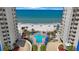 Resort-style pool with ocean view, palm trees, lounge chairs, and beach access between condo buildings at 14950 Gulf Blvd # 902, Madeira Beach, FL 33708