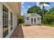 Backyard brick patio with charming shed featuring double doors and ample natural light at 15108 Winterwind Dr, Tampa, FL 33624