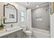 This bathroom has a gray tiled shower/tub, a sink with gray cabinets, and updated fixtures at 15108 Winterwind Dr, Tampa, FL 33624