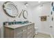 Bright bathroom featuring a double sink vanity, granite countertop, and round nautical-themed mirrors at 16106 6Th E St, Redington Beach, FL 33708