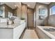 Bright bathroom with a double sink, granite countertop vanity, a soaking tub, and tiled floors at 16106 6Th E St, Redington Beach, FL 33708