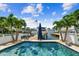 Beautiful pool view of boat dock with palms, boats, and a sunny sky at this lovely waterfront property at 16106 6Th E St, Redington Beach, FL 33708