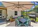 Outdoor dining area with a large umbrella and grill, surrounded by a screened enclosure and lush greenery at 1910 Montego Ct, Oldsmar, FL 34677