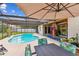 Outdoor pool area with a screened-in patio featuring a dining set and lush, tropical landscaping at 1910 Montego Ct, Oldsmar, FL 34677