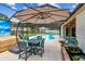 Screened-in pool area with a large patio umbrella, outdoor dining set, and lush greenery at 1910 Montego Ct, Oldsmar, FL 34677