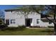 Exterior shot features a well-manicured lawn, white walls, a dark front door, white-framed windows, and trimmed hedges at 19232 Stone Hedge Dr, Tampa, FL 33647