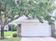 Attached one-car garage featuring stone accents and a white door, shaded by a mature tree at 19232 Stone Hedge Dr, Tampa, FL 33647