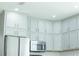 Bright kitchen featuring stainless steel appliances, light gray cabinets, and updated lighting at 19232 Stone Hedge Dr, Tampa, FL 33647