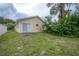 A partial view of the backyard, featuring the home's siding, sliding glass door, and surrounding foliage at 208 Oakwood Blvd, Oldsmar, FL 34677