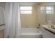 Clean bathroom featuring a tub-shower with a white shower curtain and a tiled vanity with a mirror and fixtures at 208 Oakwood Blvd, Oldsmar, FL 34677