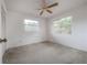 Cozy bedroom with neutral carpeting, a ceiling fan, and two windows offering natural light and views of the surrounding greenery at 208 Oakwood Blvd, Oldsmar, FL 34677