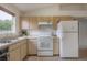 Kitchen area with white appliances and light wood cabinets under a vaulted ceiling with skylights at 208 Oakwood Blvd, Oldsmar, FL 34677