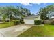 Two-car garage with a concrete driveway and neatly trimmed hedges, set against a backdrop of mature trees at 2272 Adam Ct, Palm Harbor, FL 34683