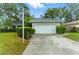 Attached garage with concrete driveway, framed by landscaped hedges and a manicured lawn under a sunny sky at 2272 Adam Ct, Palm Harbor, FL 34683