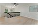 Bright hallway featuring light wood floors, modern ceiling fan, and black railing overlooking the lower level at 2272 Adam Ct, Palm Harbor, FL 34683