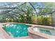 A backyard pool with a spa and a screen enclosure is surrounded by tropical landscaping at 2272 Adam Ct, Palm Harbor, FL 34683