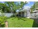 Lush backyard showcasing grassy lawn, garage with covered patio, and manicured landscaping with white fence at 2811 W Sitios St, Tampa, FL 33629