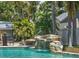 Swimming pool featuring a stunning rock waterfall, lush landscaping, and serene surroundings at 2820 Whitney Rd, Clearwater, FL 33760