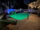 Night view of backyard pool and deck area with lights, waterfall feature, hot tub, and pergola at 2820 Whitney Rd, Clearwater, FL 33760