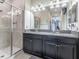 Bathroom showcasing double sinks, granite countertops, dark cabinets, and a glass enclosed shower with rainfall showerhead at 28504 Tranquil Lake Cir, Wesley Chapel, FL 33543