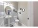 Neutral-toned powder room with a pedestal sink, round mirror, toilet, and modern decorative wall decor at 28504 Tranquil Lake Cir, Wesley Chapel, FL 33543