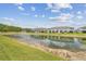 Scenic pond view featuring a fountain and the exteriors of the townhomes on a sunny day with a blue sky at 2885 Deer Pine Trl, Land O Lakes, FL 34638