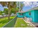 Inviting turquoise home featuring a well-manicured lawn, waterfront views, and a fenced yard, offering a relaxing outdoor space at 301 Carlyle Blvd, Ruskin, FL 33570