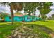 Well-maintained turquoise home with a lush green lawn and mature trees, providing a serene and inviting curb appeal in a tropical setting at 301 Carlyle Blvd, Ruskin, FL 33570