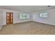 Open living room showcases wood-look floors, a front door, and multiple windows at 301 Carlyle Blvd, Ruskin, FL 33570