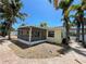 Charming backyard featuring a screened lanai, brick-paved walkway, gravel groundcover, and mature palm trees at 3014 58Th S St, Gulfport, FL 33707
